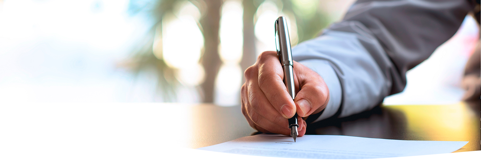 Hombre utilizando una pluma para firmar un documento
