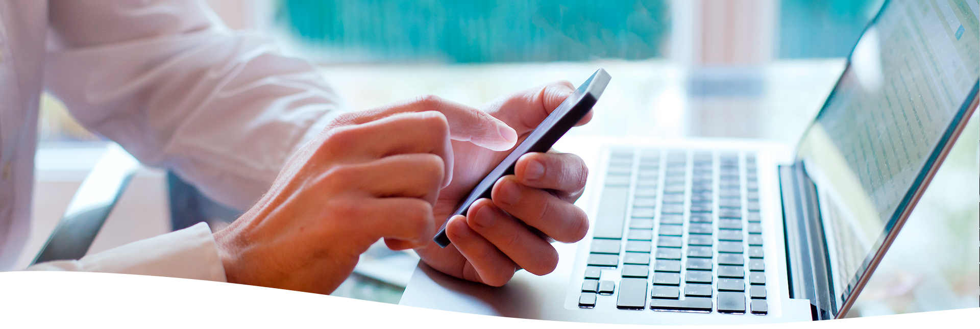 Hombre utilizando el celular y la computadora en la oficina.