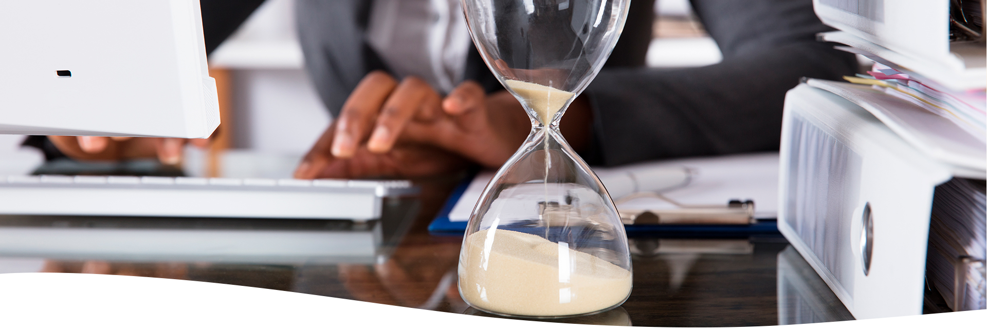 Mujer en su oficina, computadora, reloj de arena y archivos sobre el escritorio